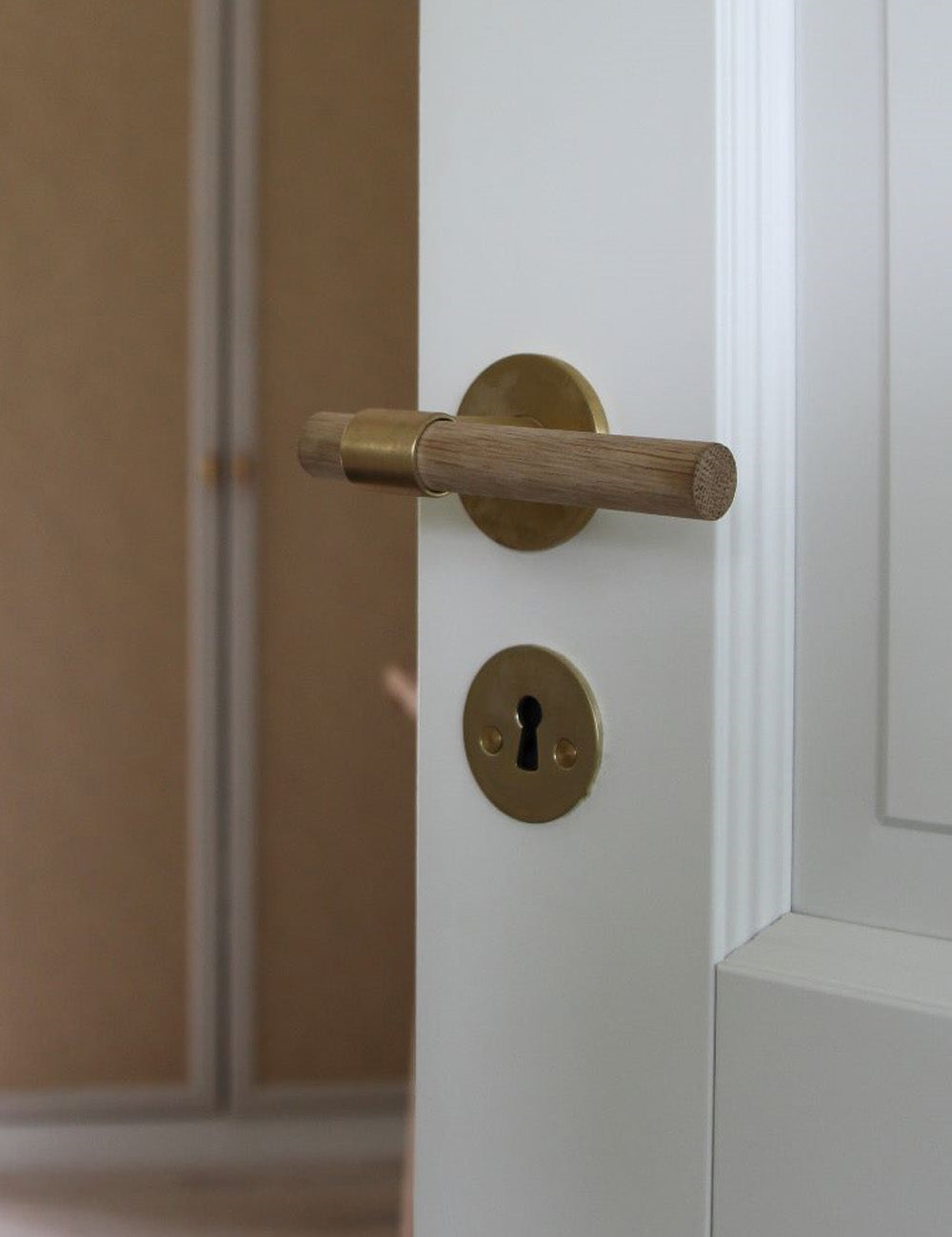 SIGNATURE door handle in Satin Brass/Oak. Modern door hardware made of solid brass by BRANDT Collective.